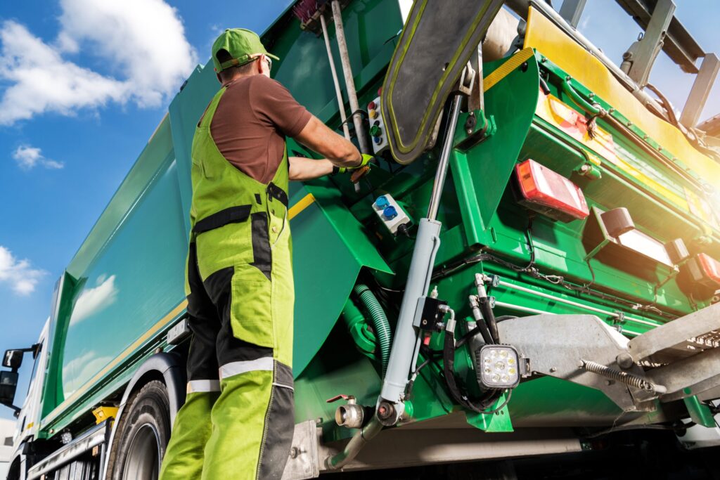 picture of a worker operating a green waste collection truck under a bright sky, on Should I use a waste broker or deal direct with haulers?